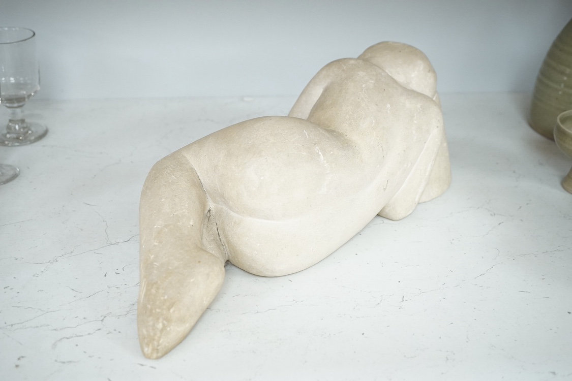 A stone carving of a sleeping nude woman, monogrammed MH, 37cm wide. Condition - fair